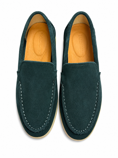 Pair of green loafers with tan soles on a white background