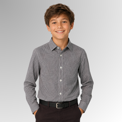 Young boy wearing a gray checkered shirt and black pants on a gray background