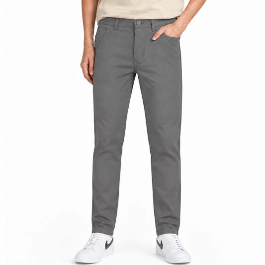 A person wearing slim-fit gray chino pants, paired with a light beige t-shirt and white sneakers, shown from the waist down on a plain white studio background.
