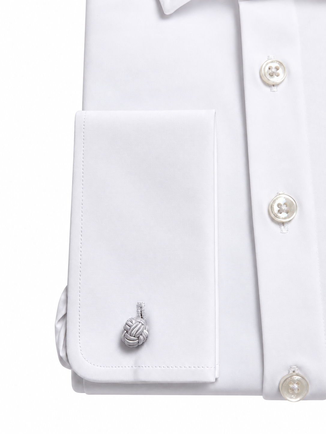 Close-up of a white dress shirt cuff with a silver-toned knotted cord cufflink, shown on a white background.